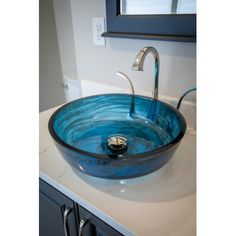 a blue bowl sink sitting on top of a counter next to a bathroom faucet