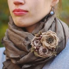 a close up of a person wearing a scarf and flower brooch on her neck