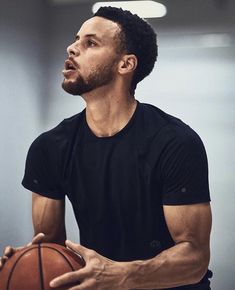 a man holding a basketball in his right hand and looking up at the sky with an intense look on his face