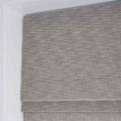 a close up of a roman blind with the blinds pulled back to reveal an off - white background