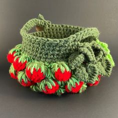 a crocheted basket with strawberries on the bottom and green trim around it