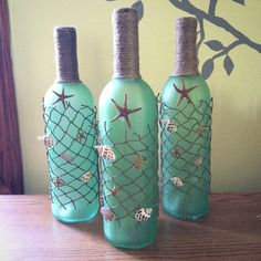 three green bottles with sea shells and starfishs on them sitting on a table