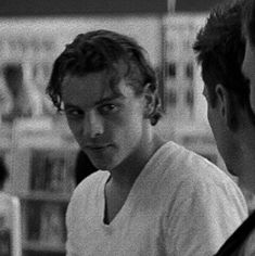 black and white photograph of two people looking at each other in front of bookshelves