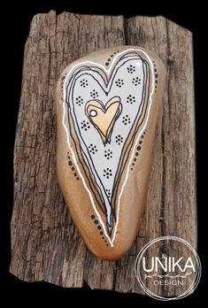 a rock with a heart painted on it sitting on top of a piece of wood