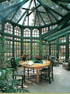 the inside of a green house with lots of windows and plants on the table in front of it