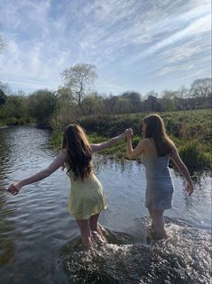 two girls in the water holding hands and touching each other's hand with their arms