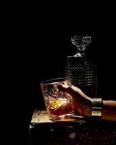 a person is holding a glass next to a decanter