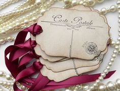 some pearls and ribbon are laying next to each other on a white table with a tag that says gate postle