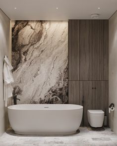 a large white bath tub sitting next to a toilet in a bathroom with marble walls