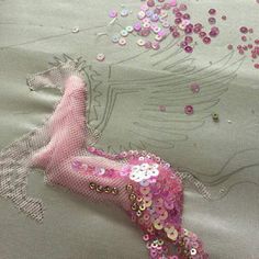 the pink mermaid is laying on the bed with sequins and beads all over it