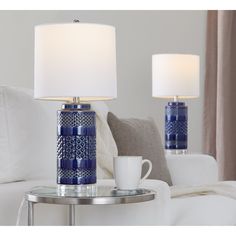 two blue and white lamps sitting on top of a table next to a coffee cup