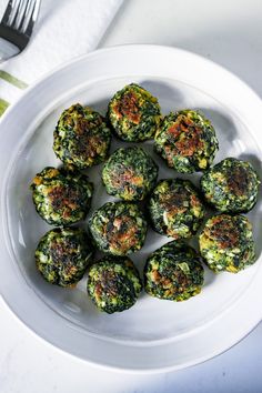 a white plate topped with mini spinach bites next to a fork and napkin on top of a table