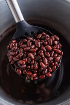 beans are being cooked in a pot with a ladle