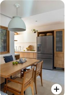 a kitchen with a table, chairs and refrigerator freezer next to it on the wall