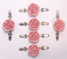 six pink roses with leaves on them sitting next to each other and two spoons