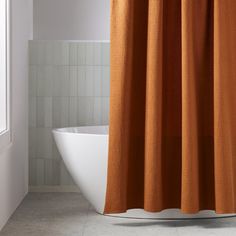 an orange shower curtain in a bathroom next to a white bathtub and toilet bowl