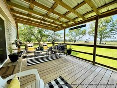 a covered porch with chairs and tables on it's side walk leading to an open field