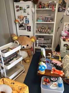 a teddy bear sitting in the corner of a room with toys and books on shelves