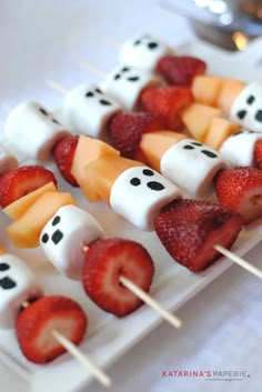 marshmallows and strawberries are arranged on skewers with faces painted on them