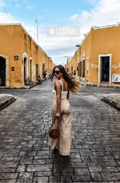 a woman is walking down the street with her hair blowing in the wind