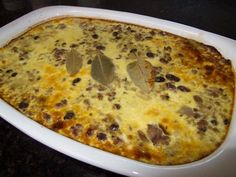 a casserole dish with meat and cheese in it sitting on a black table