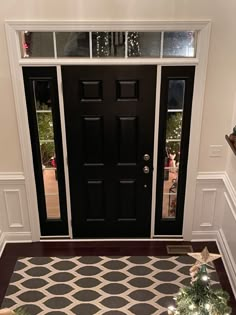 a black and white christmas tree is in front of a door with lights on it