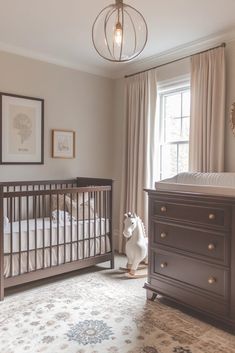 a baby's room with a crib, dresser and window in the corner