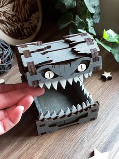 a hand is opening up a wooden box with an animal's face on it