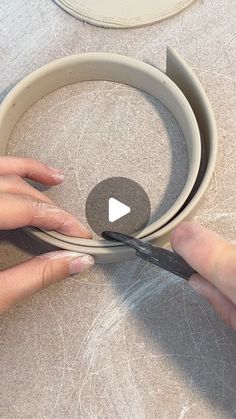 a woman is using scissors to cut the edge of a round object