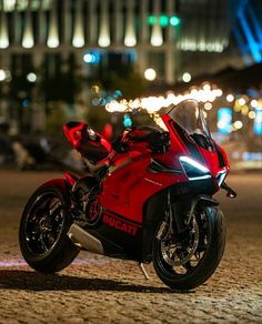 a red motorcycle parked on top of a street next to a tall building at night