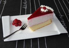 a piece of cake on a white plate with raspberries