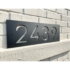 a metal house number sign mounted on a brick wall with the numbers twenty and thirty