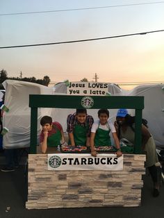 some people are standing behind a sign for starbucks