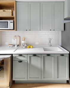 a kitchen with gray cabinets and white counter tops