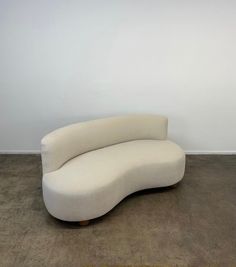 a curved white couch sitting in an empty room