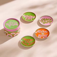 four small round tins sitting on top of a white surface