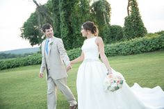 a bride and groom holding hands in the grass