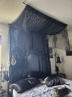 a cat laying on top of a black bed in a room with white walls and curtains