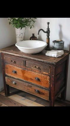 a bathroom sink sitting on top of a wooden dresser next to a potted plant