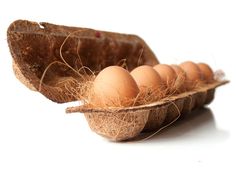 several eggs in a cardboard container on a white surface