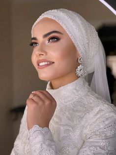 a woman in a white dress and veil posing for the camera with her hands on her hips