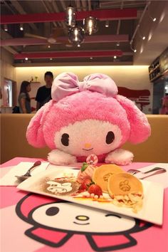 a pink stuffed animal sitting on top of a table next to a plate of food