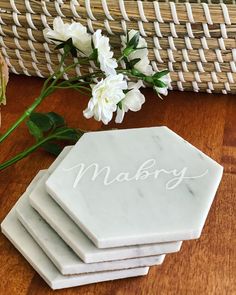 marble coasters with the word mabry written on them next to flowers and wicker basket