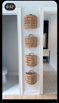 three wicker baskets are hanging on the wall in this hallway with white walls and wood flooring