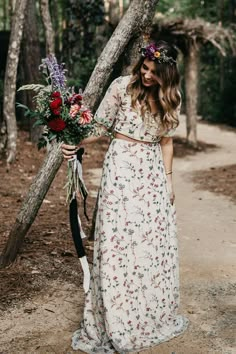 a woman in a floral print dress holding a bouquet of flowers and wearing a flower crown