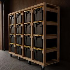 a large wooden shelf with many black bins on it's sides and wheels