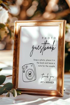 a photo frame sitting on top of a table next to some flowers and greenery