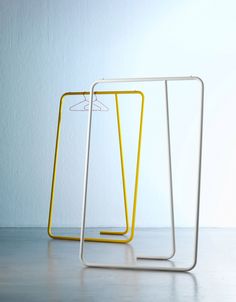 two yellow and white racks sitting next to each other on top of a table in front of a wall