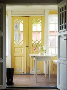 an open door leading into a room with yellow doors and white table in the center