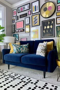 a living room filled with furniture and lots of framed pictures on the wall above it